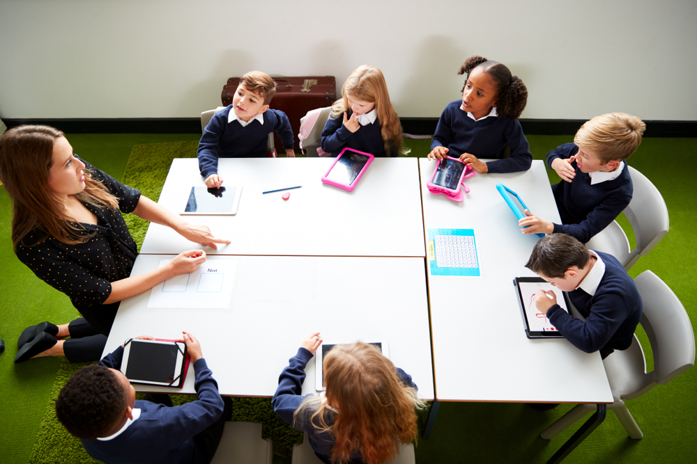 Children sat around a table with a teacher in a session